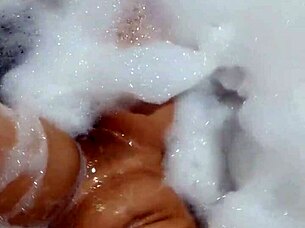 A gorgeous brunette enjoys herself in the hotel bathtub